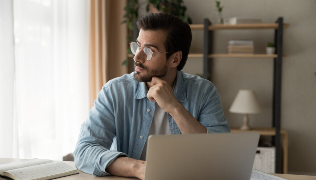 Pensive,Young,Guy,Employee,Sit,At,Workplace,Look,Aside,Of