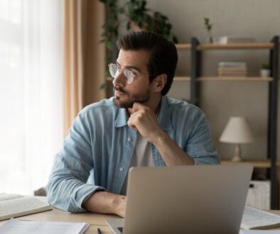 Pensive,Young,Guy,Employee,Sit,At,Workplace,Look,Aside,Of
