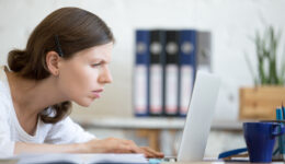 Young,Stressed,Businesswoman,Sitting,With,Laptop,And,Looking,At,Screen